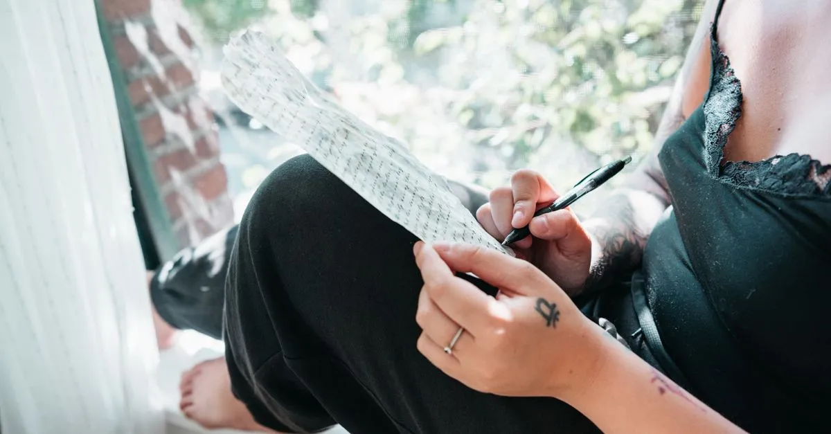 Persona escribiendo una reflexión en su diario junto a la ventana
