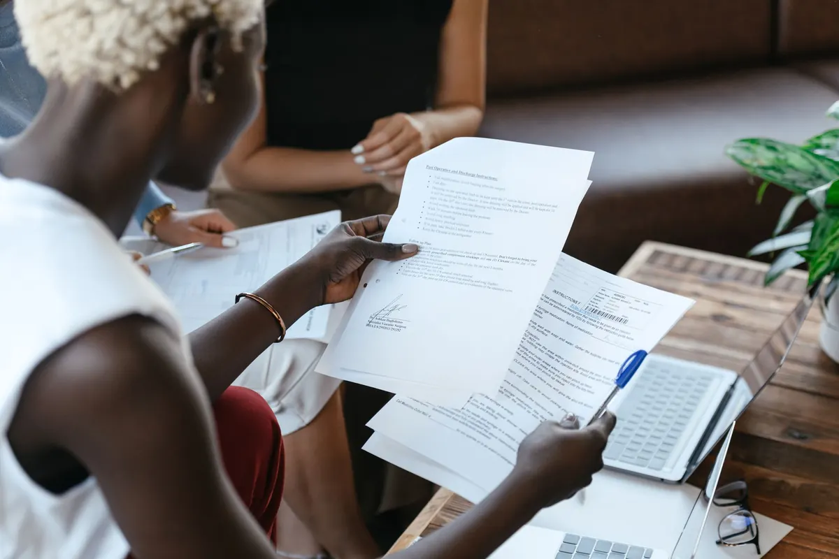 Persona con dos cartas de oferta laboral sobre la mesa y una libreta con anotaciones