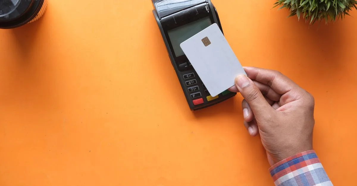 Mano insertando una tarjeta bancaria en una terminal de pago