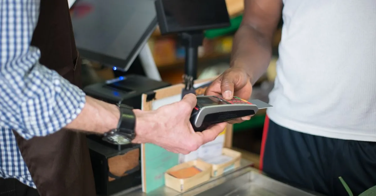 Persona entregando una tarjeta bancaria en el mostrador de un comercio