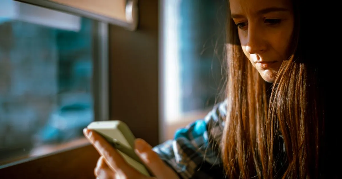 Persona pensativa mirando redes sociales en su teléfono