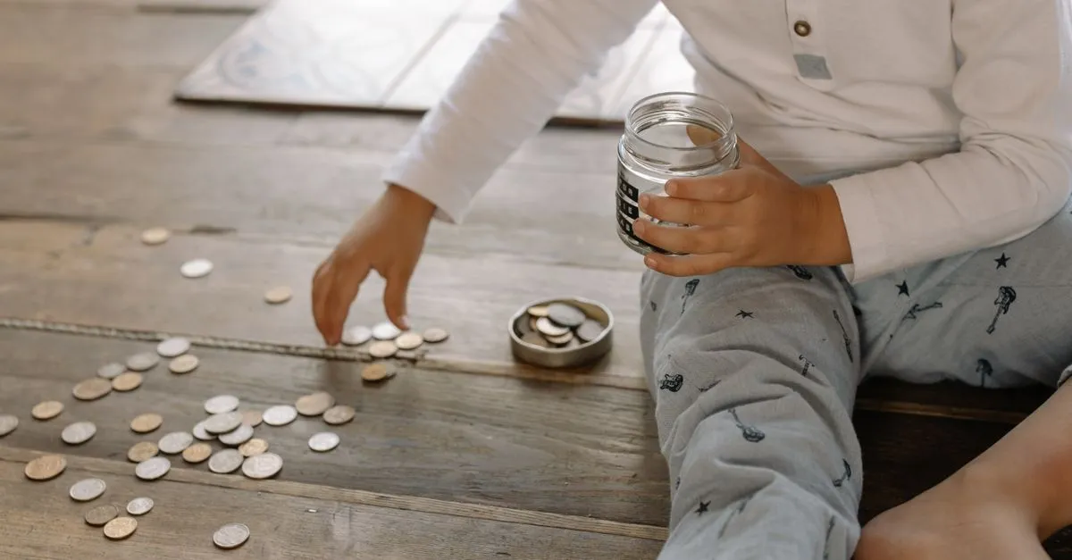 Niño contando las monedas de su frasco de ahorro