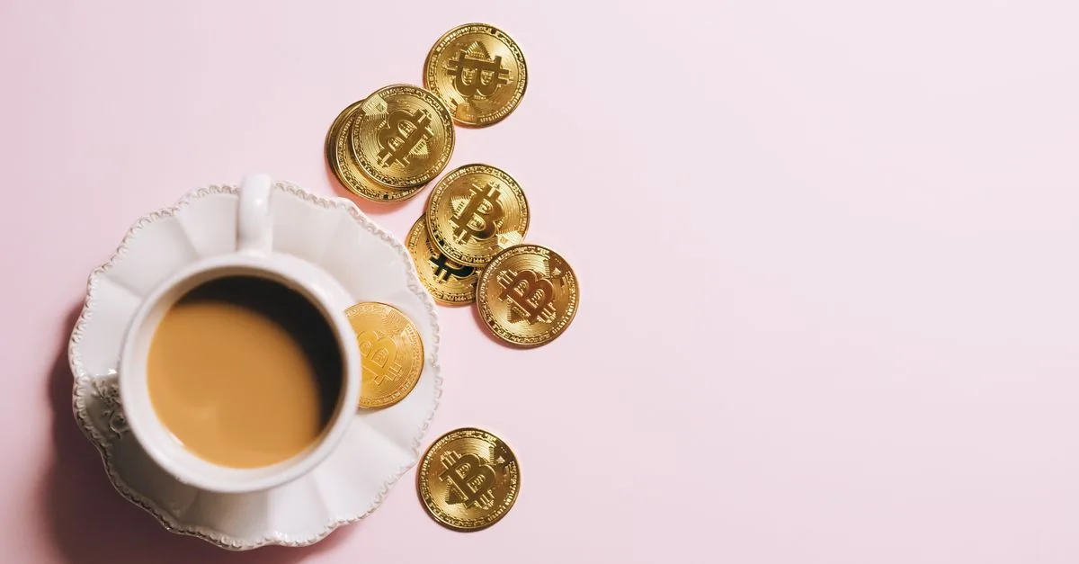 Taza de café y monedas sobre la mesa, ejemplo de gastos hormiga