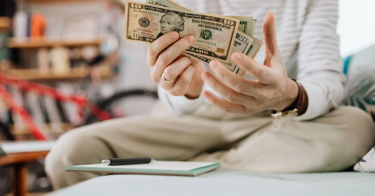 Persona contando billetes que representan su ingreso