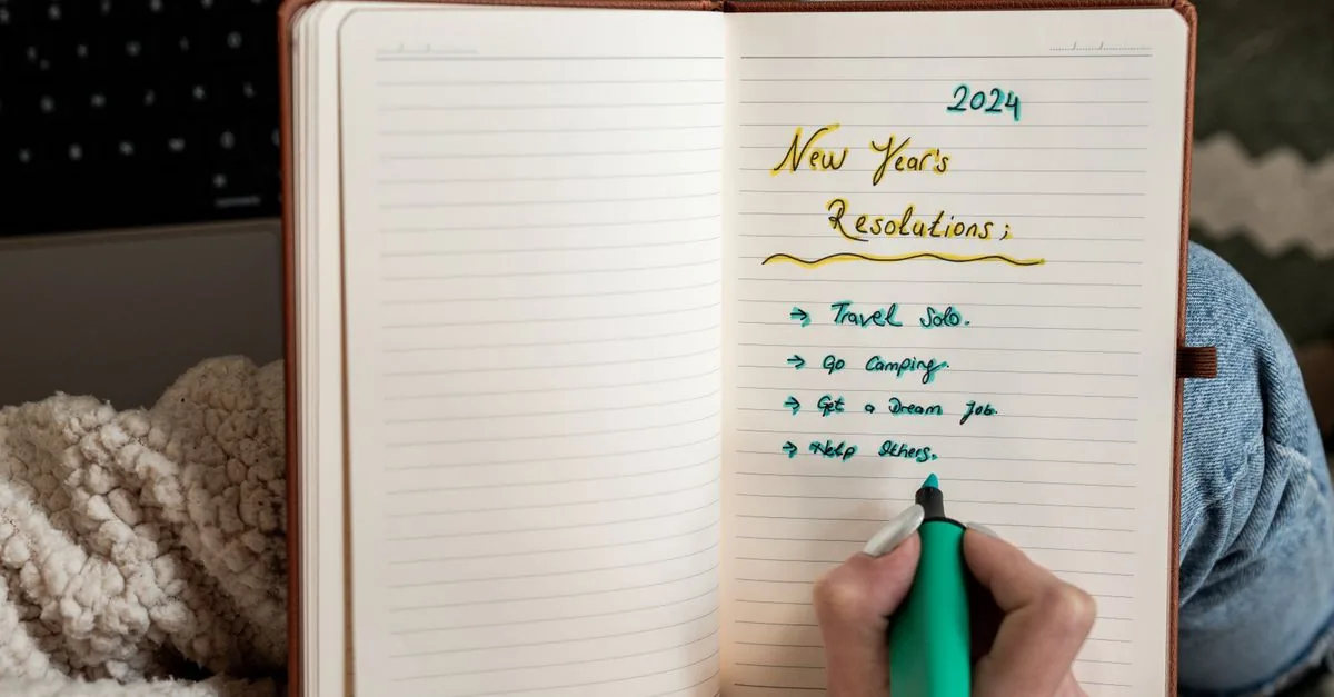 Mano escribiendo metas en una libreta
