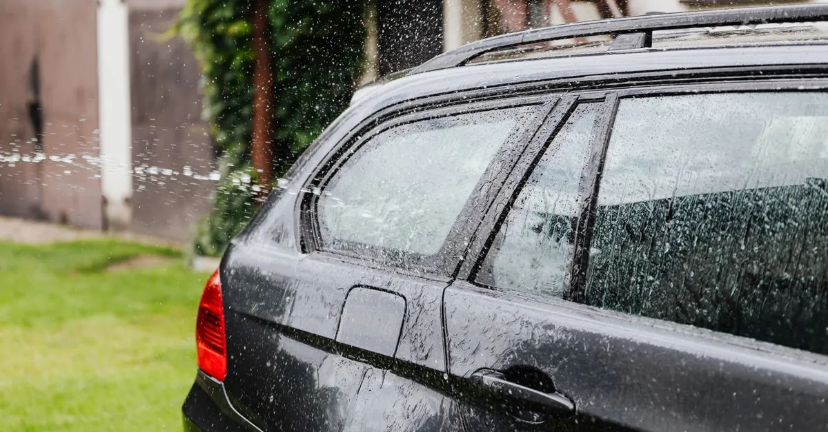 Coche de varios años lavado en la entrada de una casa modesta
