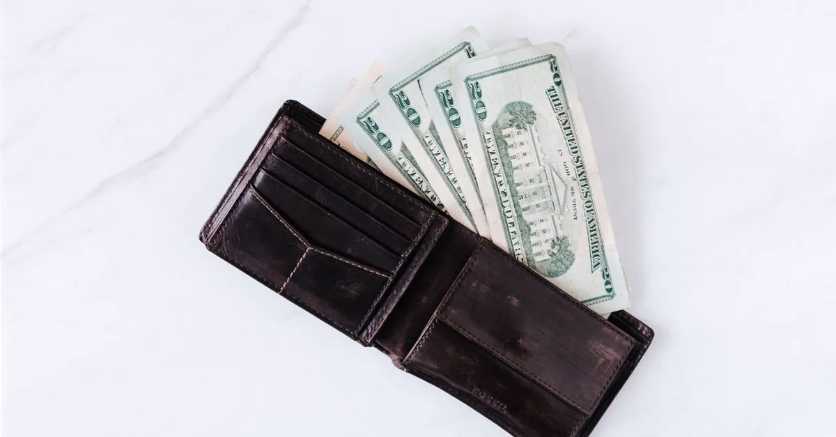 Cartera abierta con el efectivo de la semana sobre la mesa