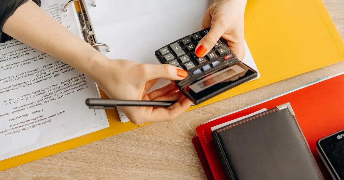 Manos usando una calculadora sobre documentos financieros
