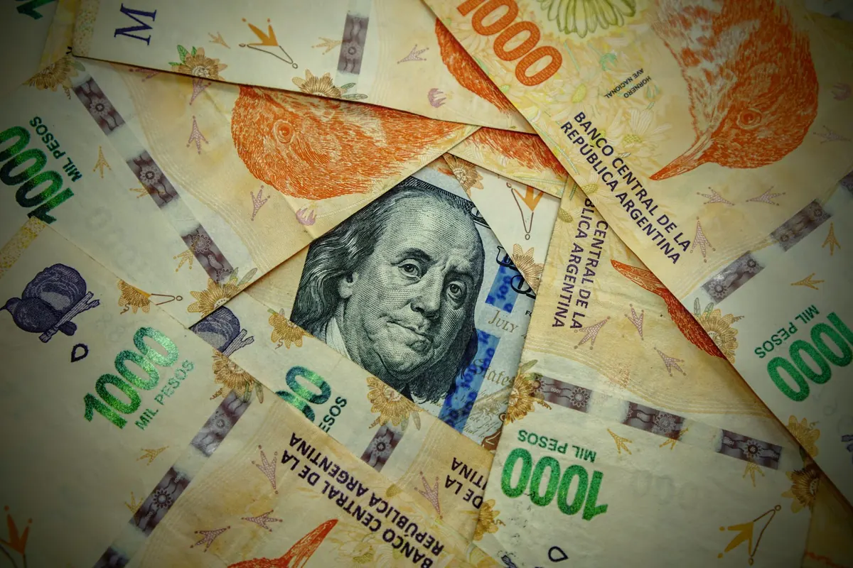 Billetes de peso y de dólar sobre una mesa comparando su valor