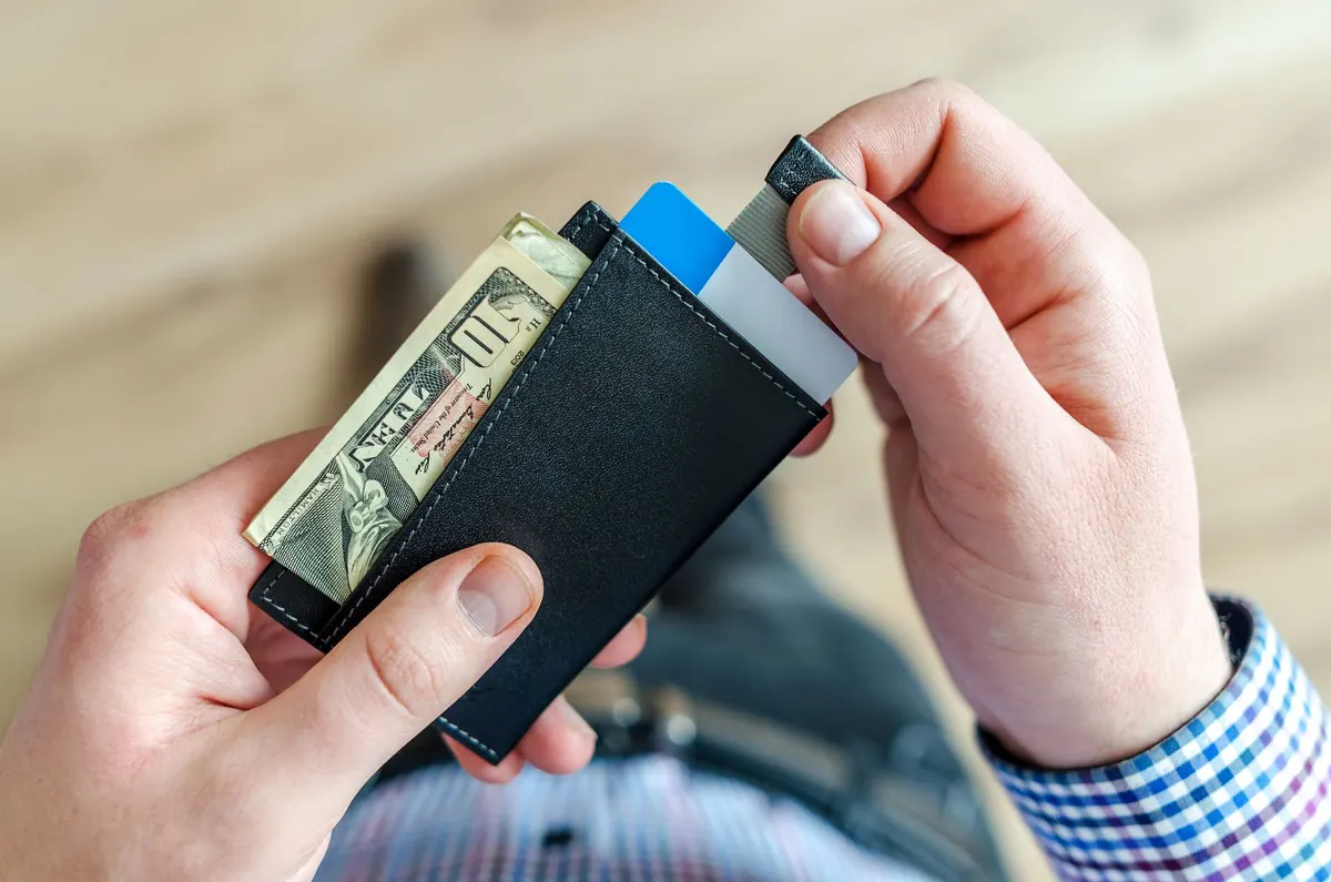 Manos contando billetes junto a un teléfono con la app del banco abierta
