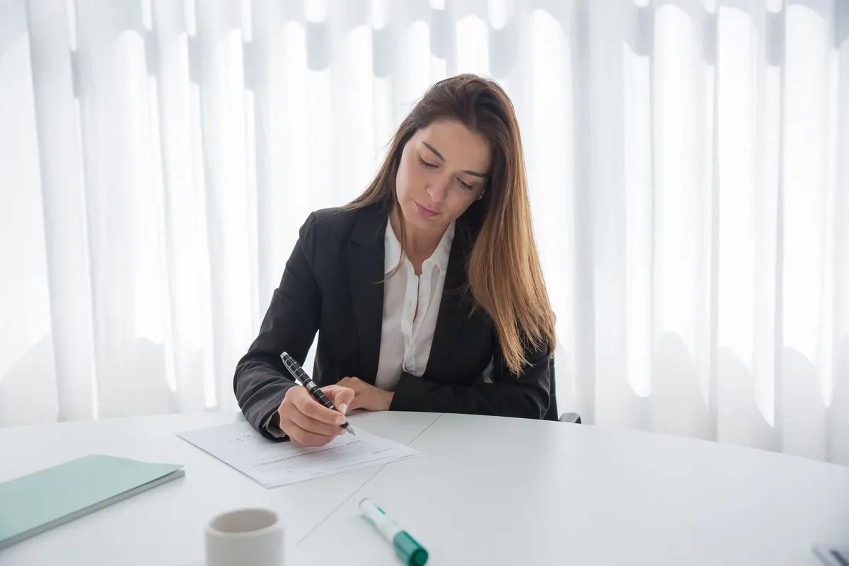 Dos personas revisando un contrato sobre una mesa con una pluma al lado