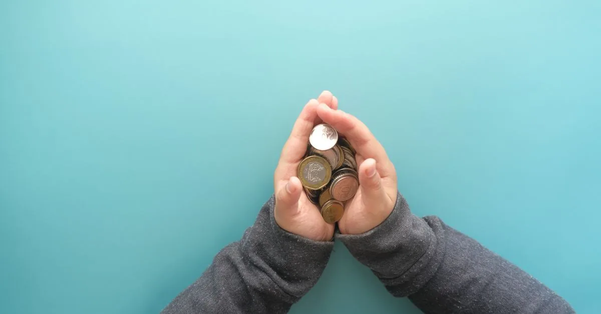 Varias manos alrededor de monedas apiladas, un fondo que reúne el dinero de muchos