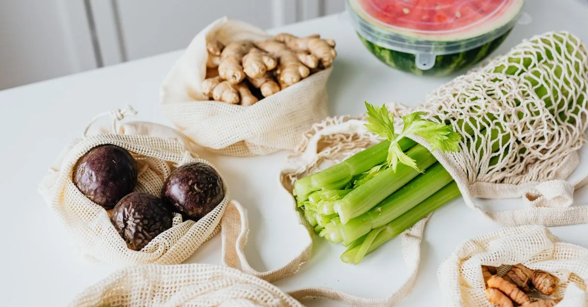 Despensa de verduras frescas en bolsas de tela sobre la mesa de una cocina
