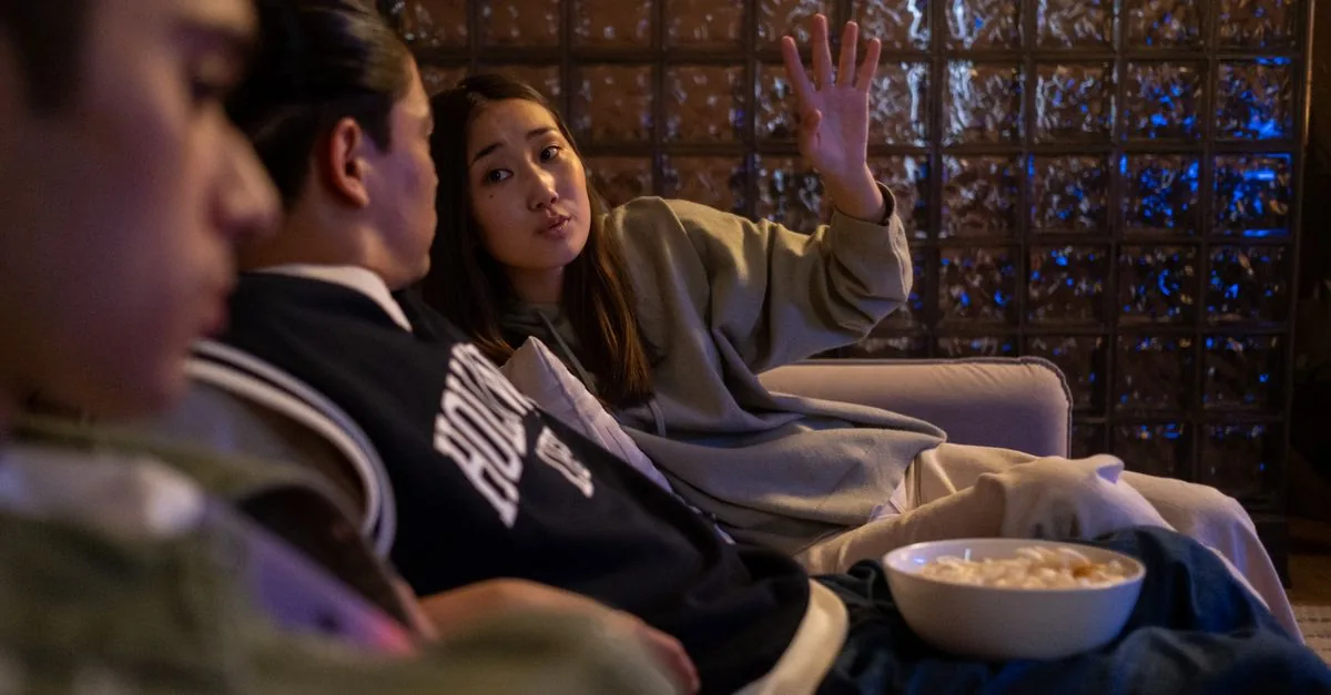 Amigos viendo una película en casa con palomitas, plan de entretenimiento barato