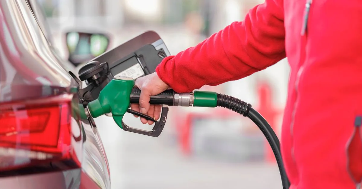 Persona cargando gasolina en su auto en una estación de servicio