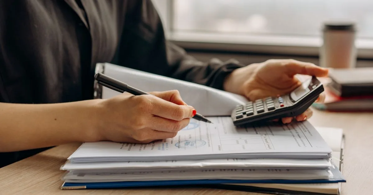Persona revisando su recibo de nómina con una calculadora