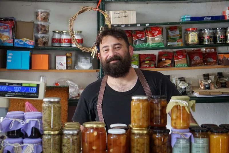 Dueño de una tienda pequeña sonriendo detrás del mostrador